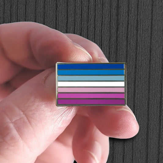 Hand holding a flag pin with horizontal stripes on a dark background