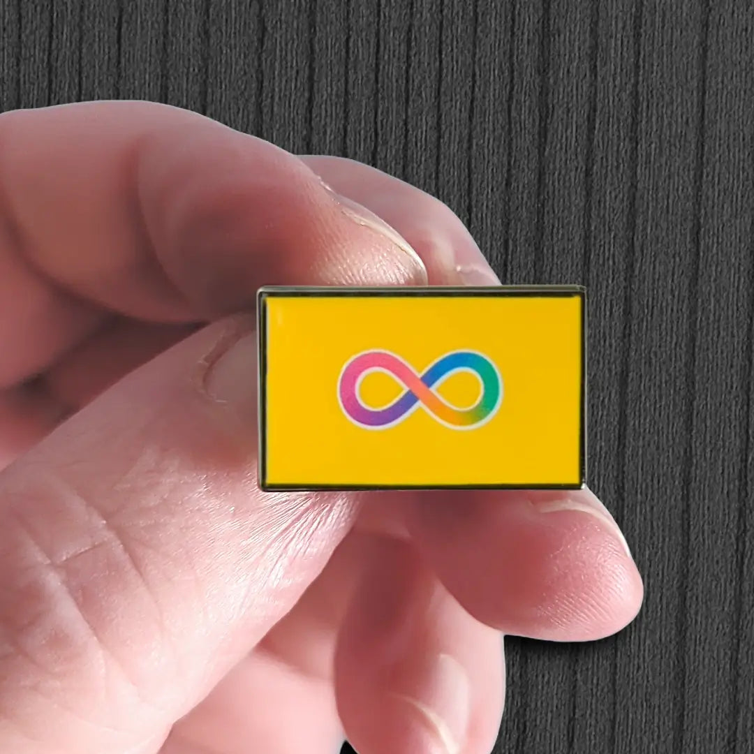 Hand holding a rectangular pin with a colorful infinity symbol on a yellow background