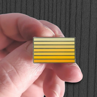 Hand holding a rectangular object with yellow and white striped pattern against a dark background