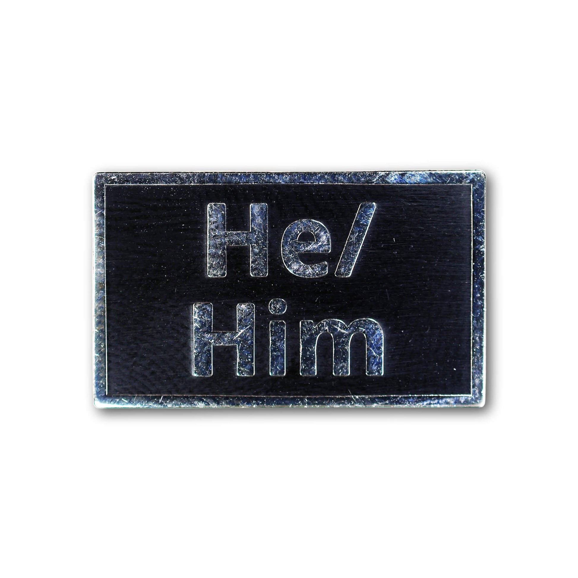 Black rectangular enamel pin with 'He/ Him' text on a white background