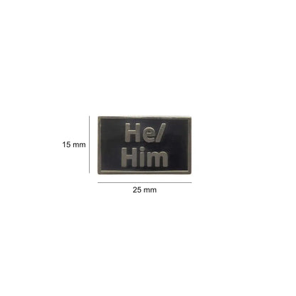 Black He/Him lapel pin with metallic raised text, shown with dimensions of 25mm wide and 15mm tall compact and stylish, perfect for jackets, backpacks, or lanyards.