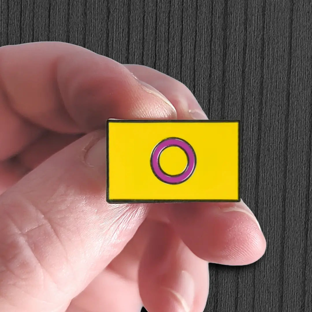 Yellow square with a purple circle held by a hand against a dark background