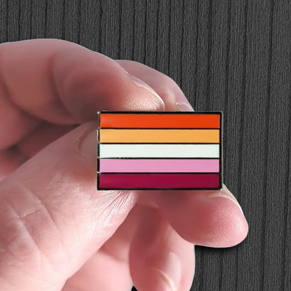 Colorful striped pin held between fingers against a dark background