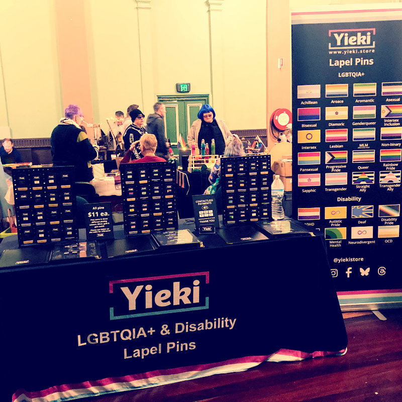 Yieki stall with LGBTQIA+ and disability lapel pins at an event