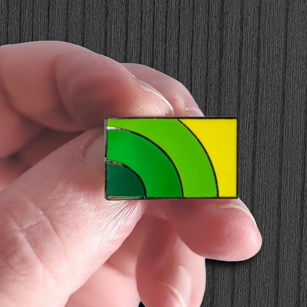 Hand holding a rectangular object with green and yellow design against a dark background