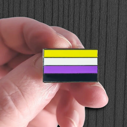 Hand holding a small flag with yellow, white, and purple stripes against a dark background