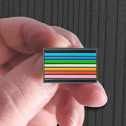 Hand holding a small rectangular object with horizontal stripes against a dark background