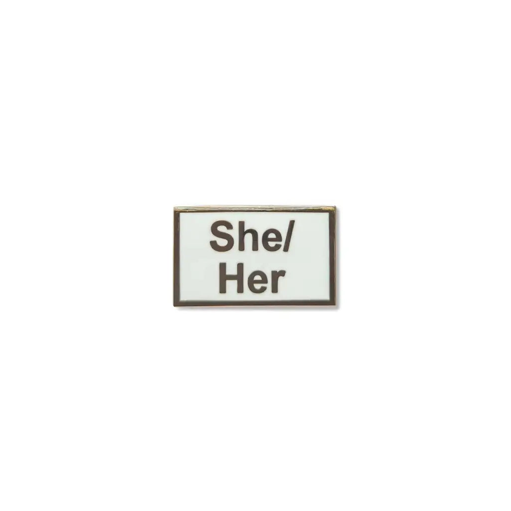 Rectangular She/Her lapel pin with a crisp white enamel background and bold black lettering, framed in a fine metallic outline a minimalist, gender-affirming accessory.