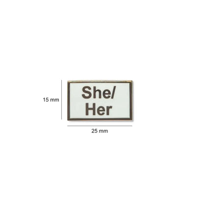 White She/Her lapel pin with black text, shown with measurements of 25mm wide by 15mm tall compact, polished, and perfect for visibility on clothing or bags.