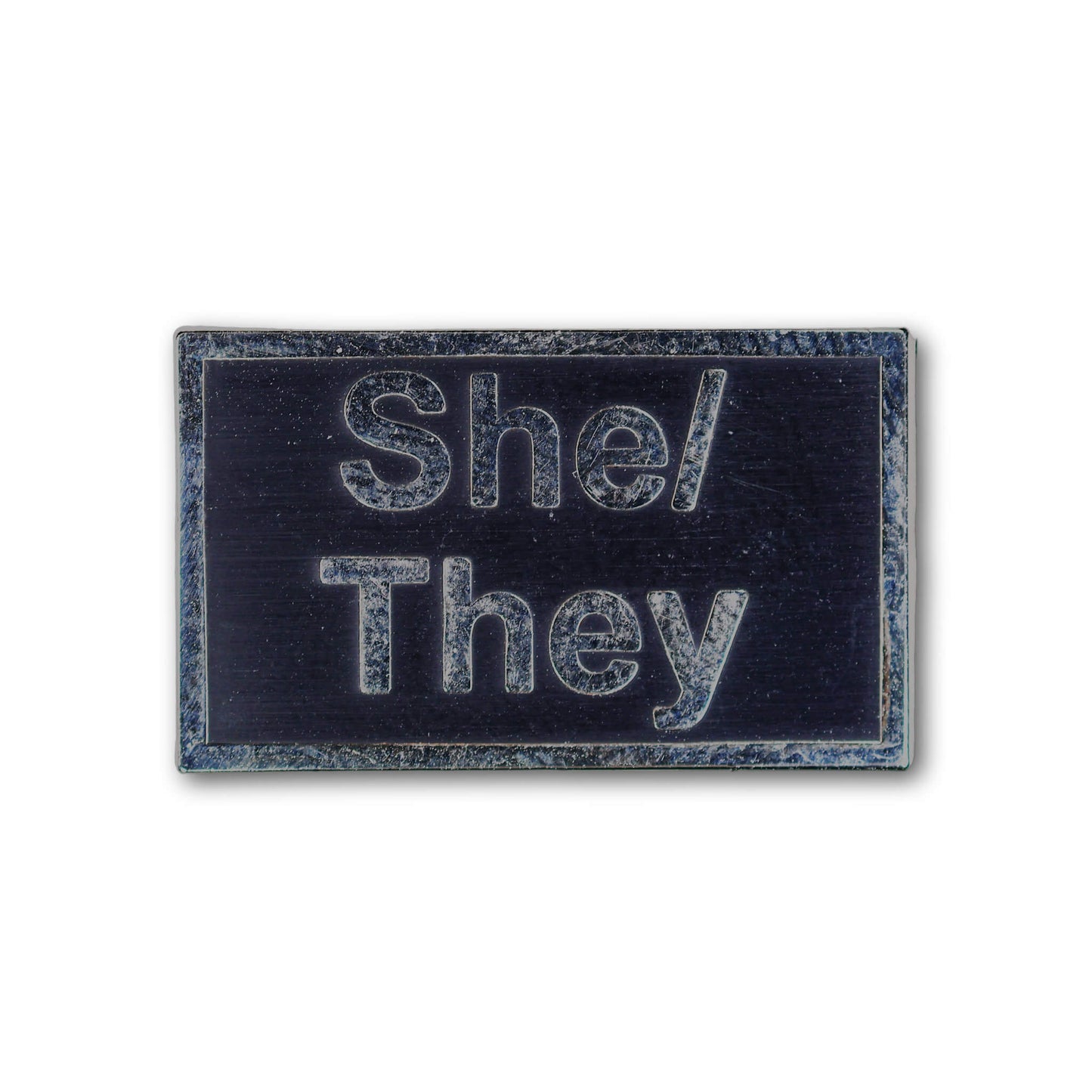 Rectangular patch with 'She/They' text on a black background