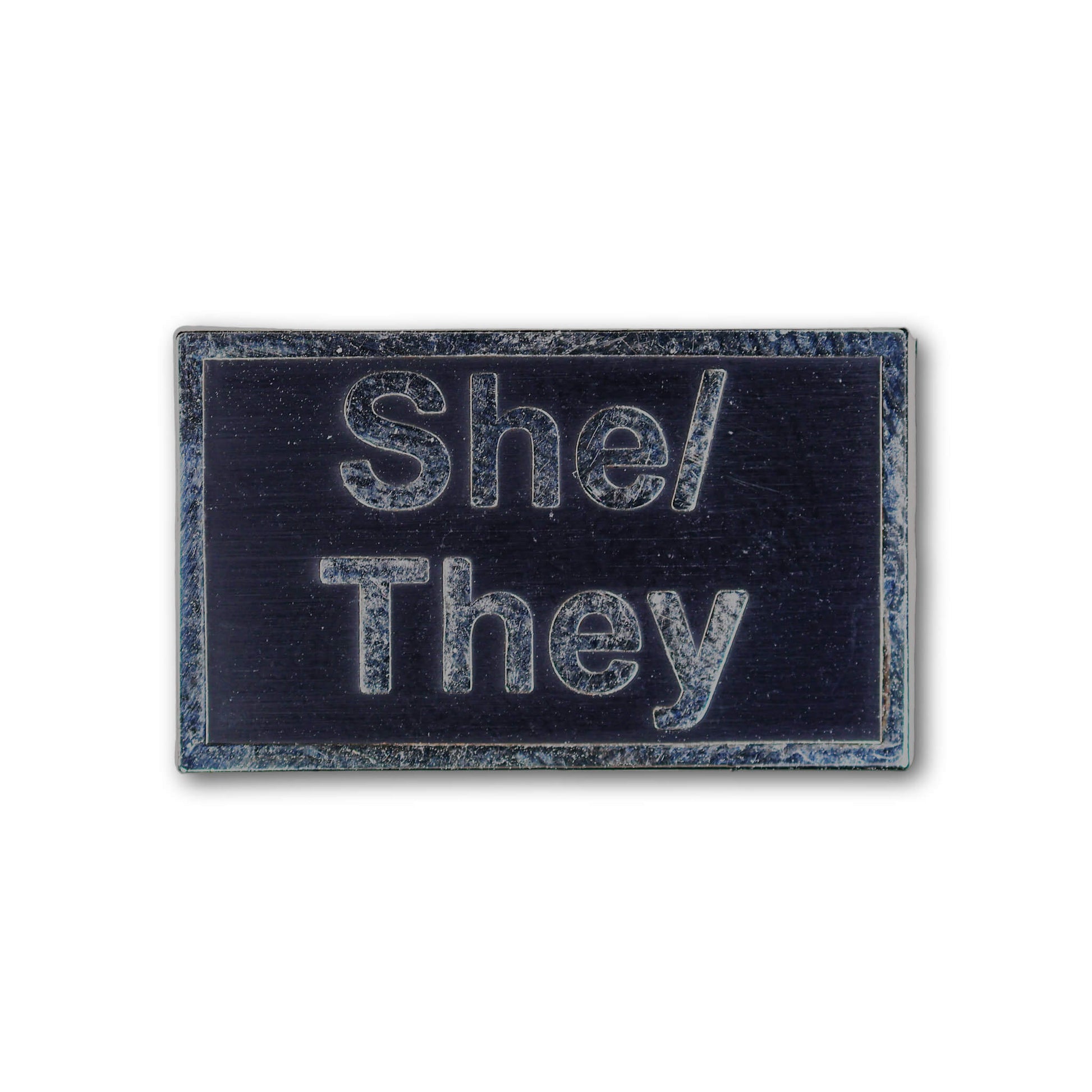 Rectangular patch with 'She/They' text on a black background