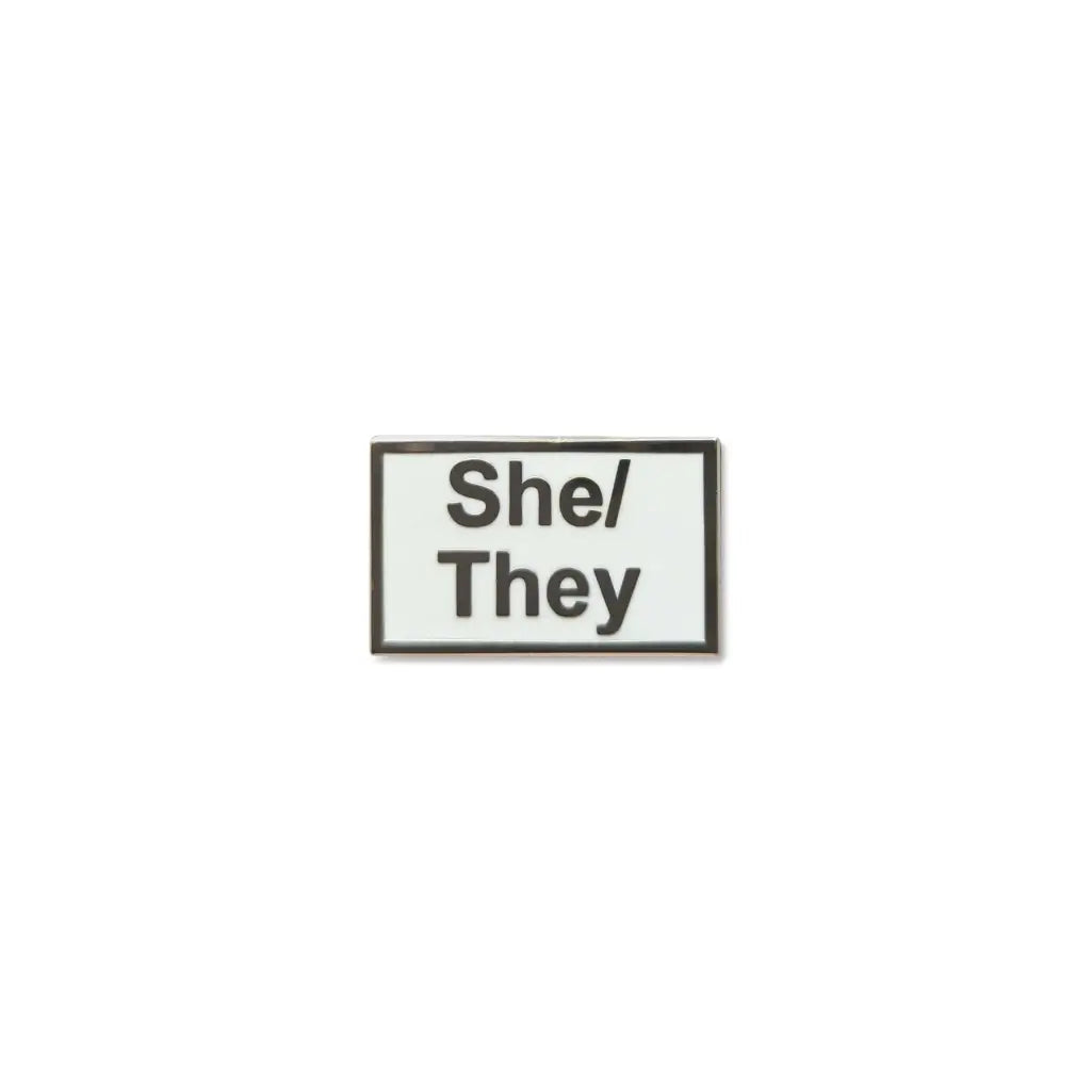 Rectangular She/They lapel pin with a white enamel background, bold black text.