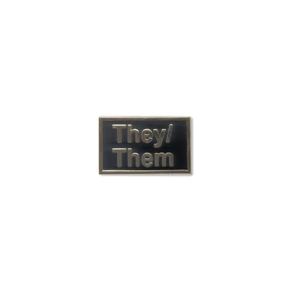 Minimalist They Them lapel pin with dark lettering on a clean white enamel background, designed to highlight nonbinary pronouns in a subtle and stylish way