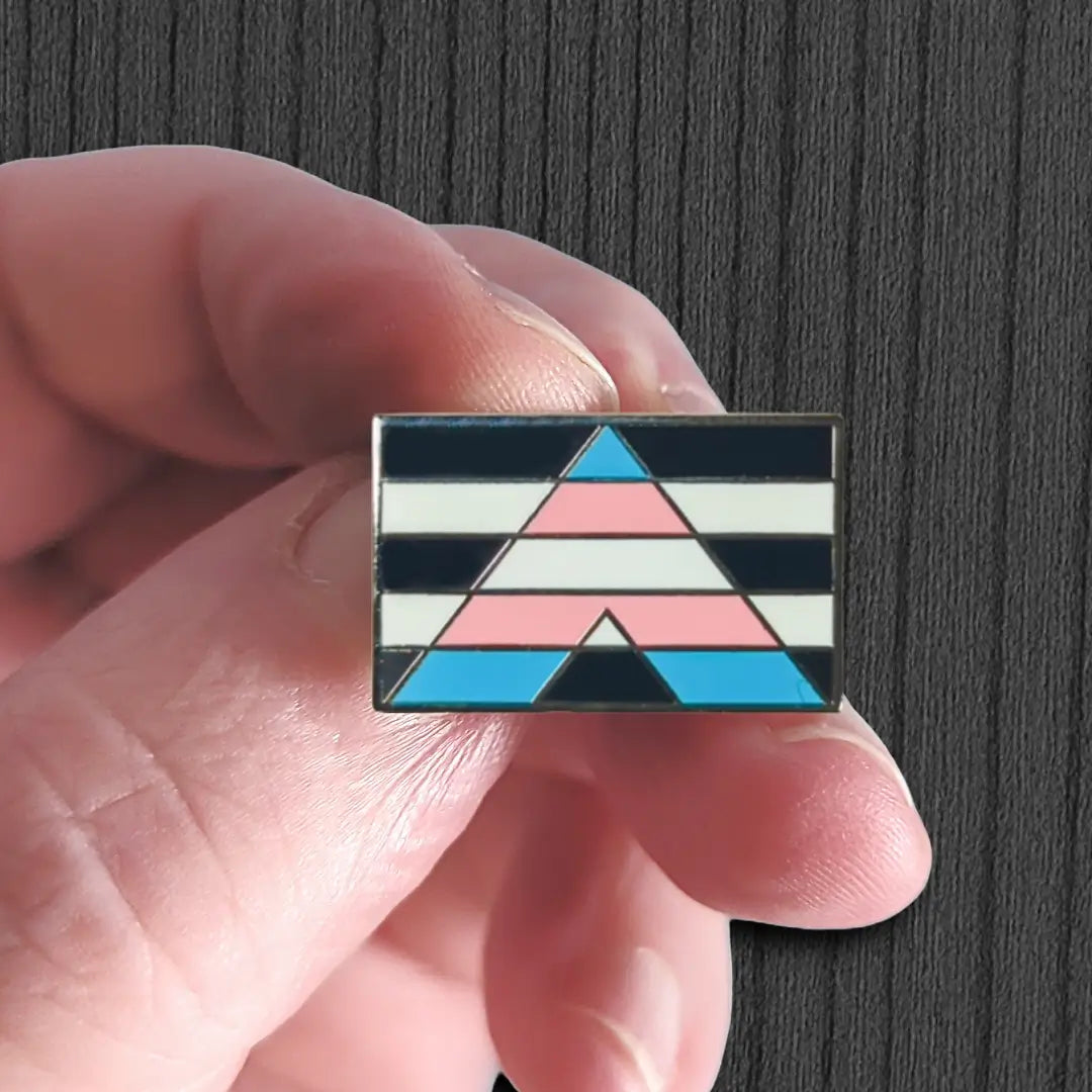 Hand holding a geometrically patterned pin against a dark background